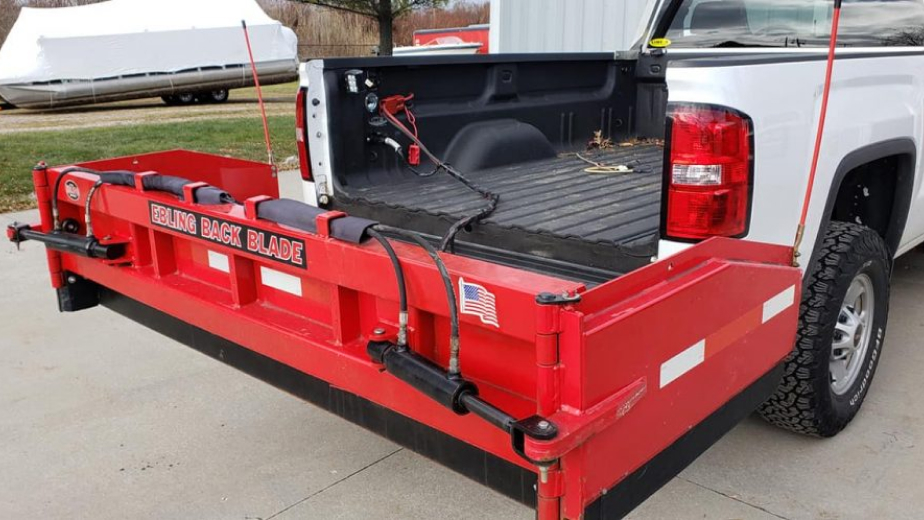 Picture of a red back blade attached on a white truck.